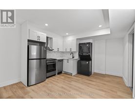 A modern kitchen with wooden floors and stainless steel appliances.