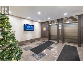A Christmas tree is in the corner of a room with a TV mounted on the wall.