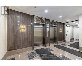 A hallway with a glass elevator and a wooden wall.
