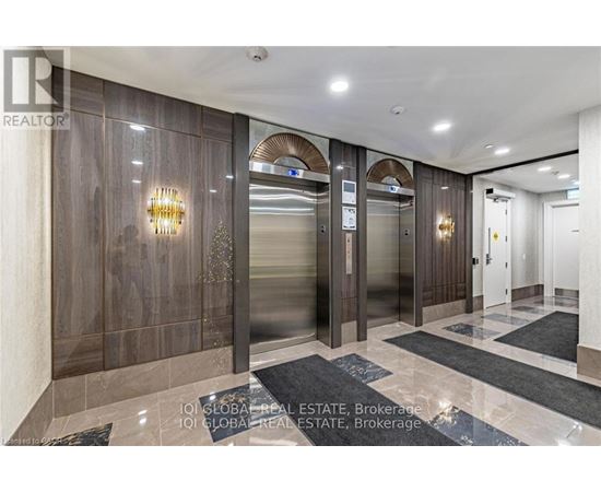 A hallway with a glass elevator and a wooden wall.