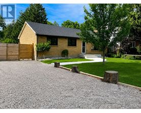 A house with a gravel driveway and a tree in front.