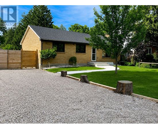 A house with a gravel driveway and a tree in front.