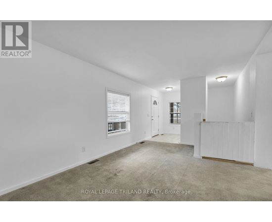 A white room with a carpet floor and a window with blinds.