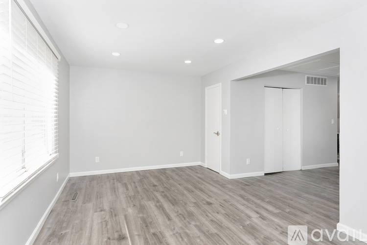 A spacious room with wooden flooring and white walls.