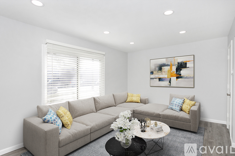 A living room with a grey couch, a coffee table, and a painting on the wall.