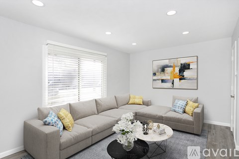A living room with a grey couch, a coffee table, and a painting on the wall.