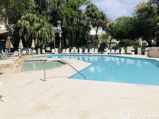 A large outdoor pool surrounded by trees and lounge chairs.