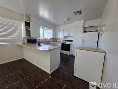 A kitchen with white cabinets and a wooden floor.