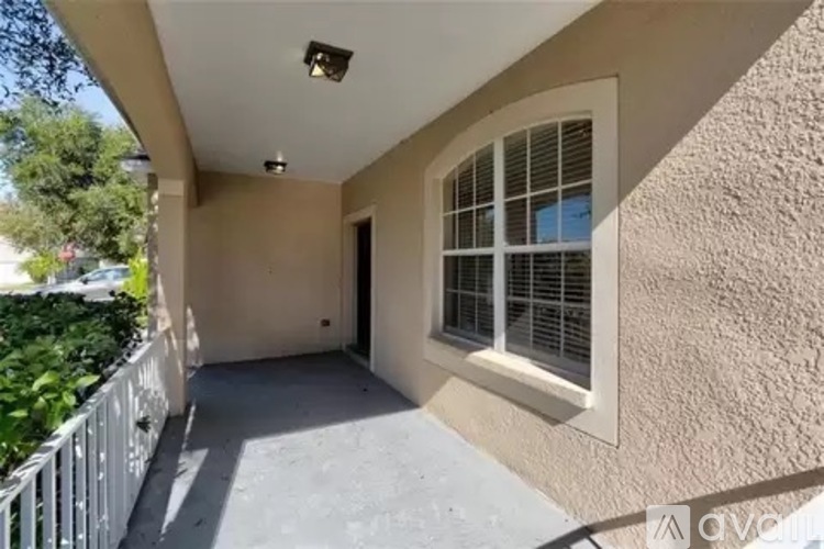 A patio area with a white railing, a window with blinds, and a door.