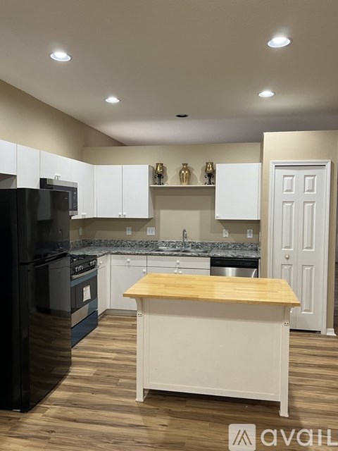 A kitchen with white cabinets and a wooden island.