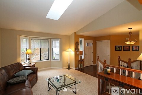 A living room with a brown couch and a glass coffee table.