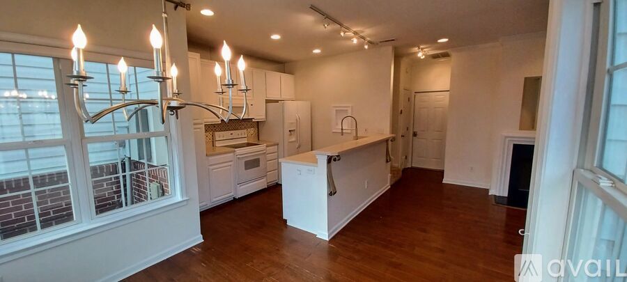 A large, empty kitchen with white cabinets and a wooden floor.