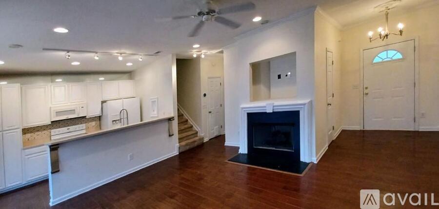 A spacious living room with a fireplace and a kitchen area in the background.