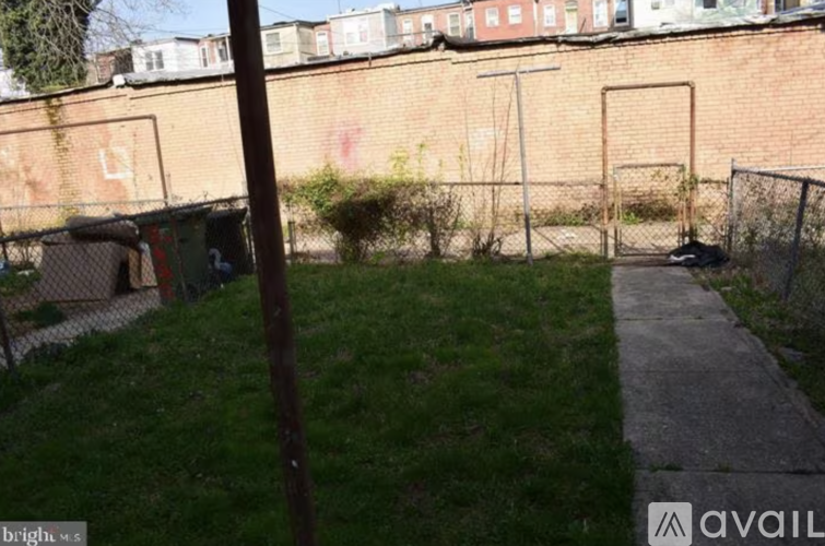 A grassy area with a fence and a brick wall in the background.