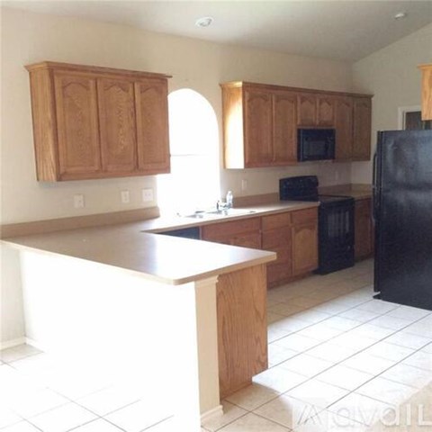 A kitchen with wooden cabinets and a black refrigerator.