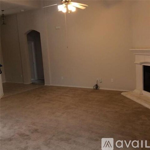 A spacious room with a fireplace and a fan on the ceiling.