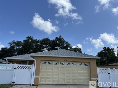 A house with a garage and a white fence in front.