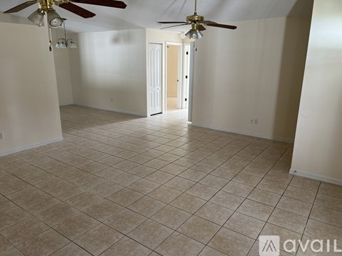 A spacious room with a ceiling fan and tiled flooring.