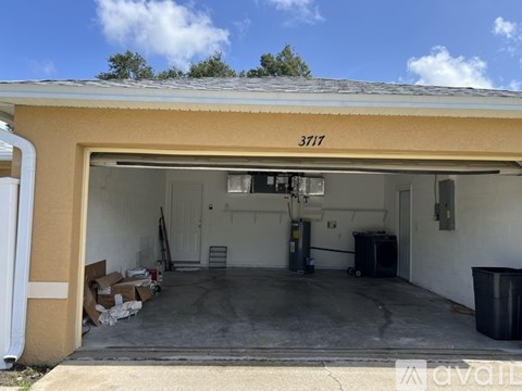 A garage with boxes on the floor and a trash can to the right.