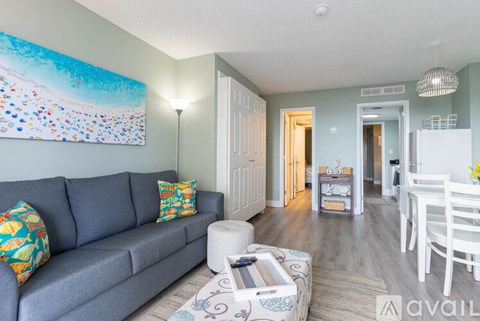 A living room with a grey couch and a painting on the wall.