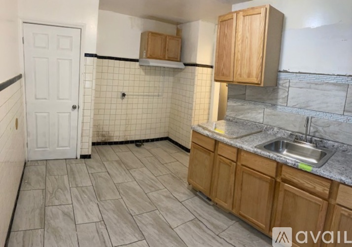 A kitchen with a white door, wooden cabinets, and a marble countertop.
