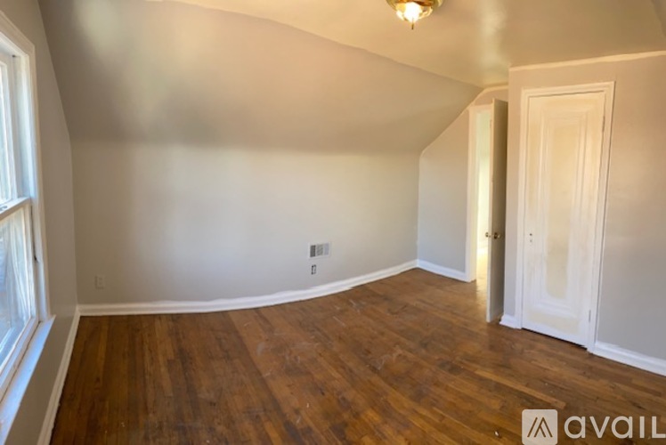 A room with wooden floors and white walls, with a door on the right side.