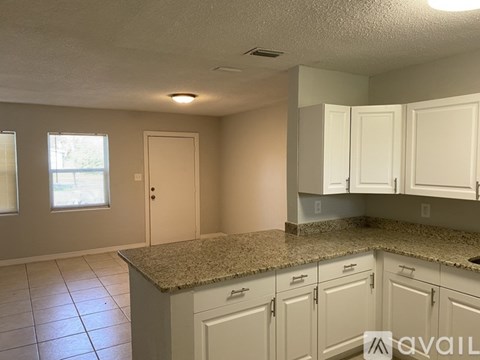 A kitchen with white cabinets and a granite countertop.