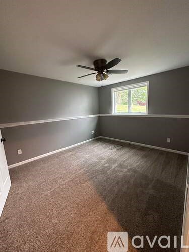A room with a ceiling fan and carpeted floor.