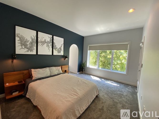 A bedroom with a large bed and a window with a view of trees.