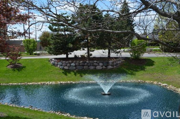 A fountain in the middle of a pond surrounded by a stone wall.