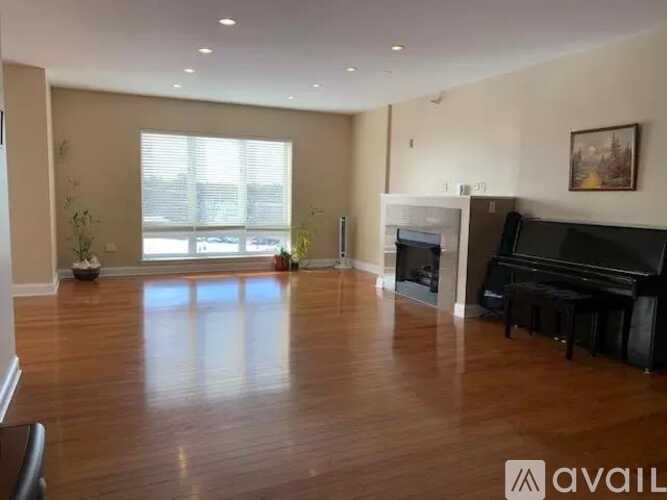 A spacious living room with a piano and a fireplace.