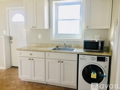 A kitchen with white cabinets and a washer and dryer on the counter.