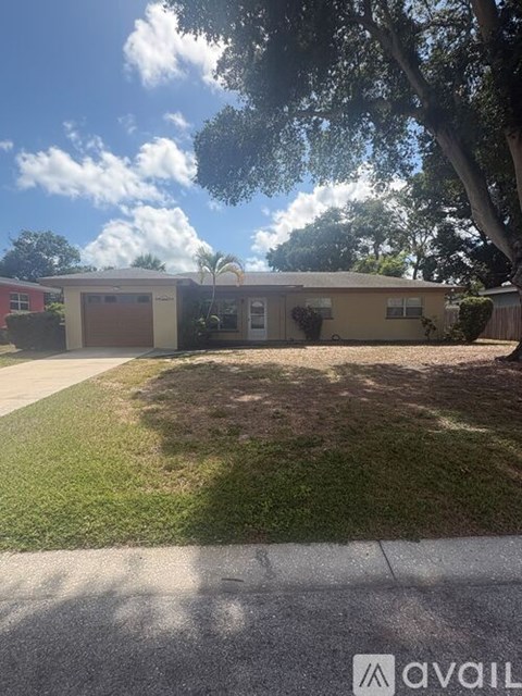 A house with a garage and a tree in front.