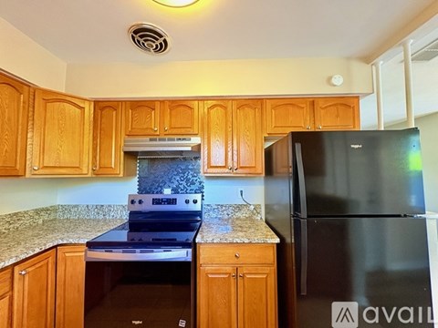 A kitchen with wooden cabinets and a black fridge.