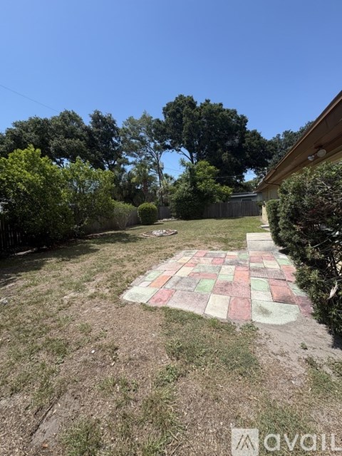 A backyard with a tiled patio and a wooden fence.