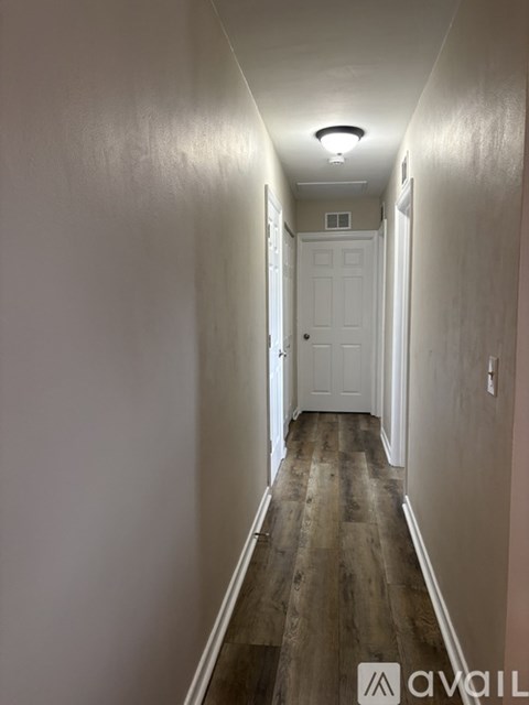 A long hallway with a white door at the end.