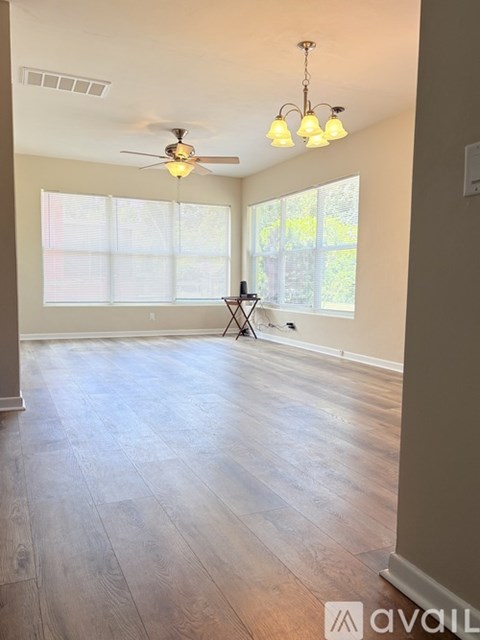 A spacious room with a ceiling fan and lighting fixture.