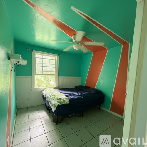 A bedroom with a bed, a ceiling fan, and a window.