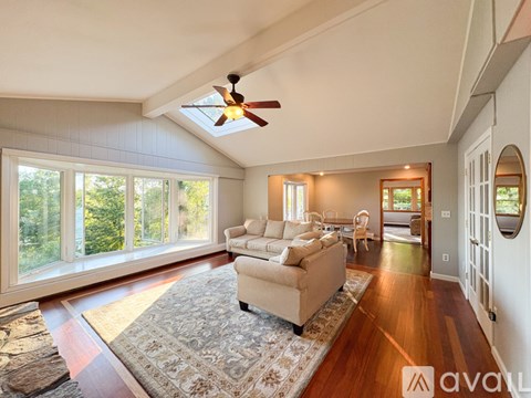 A living room with a beige couch and a rug in front of a large window.