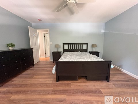 A bedroom with a bed, dresser, and ceiling fan.