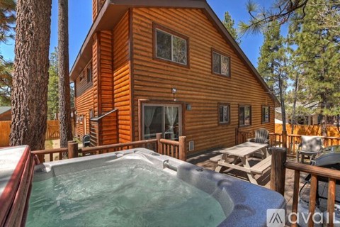 A wooden cabin with a hot tub in front.