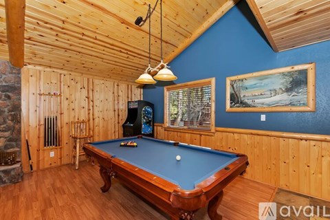 A pool table in a room with wooden walls and a ceiling.