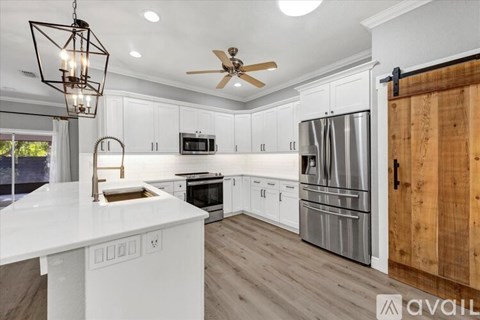 A modern kitchen with white cabinets and a wooden door.