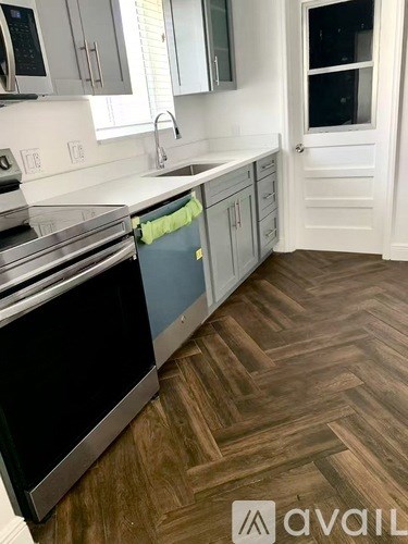 A kitchen with a black oven and wooden flooring.