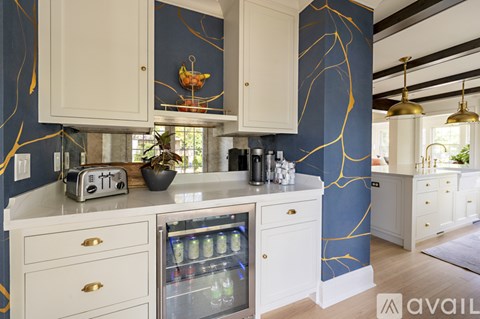 A kitchen with white cabinets and a blue wallpapered wall.