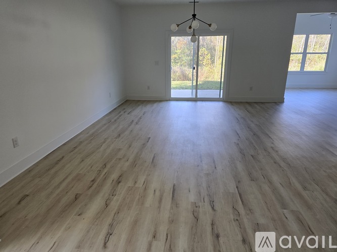 A spacious room with wooden flooring and a chandelier.