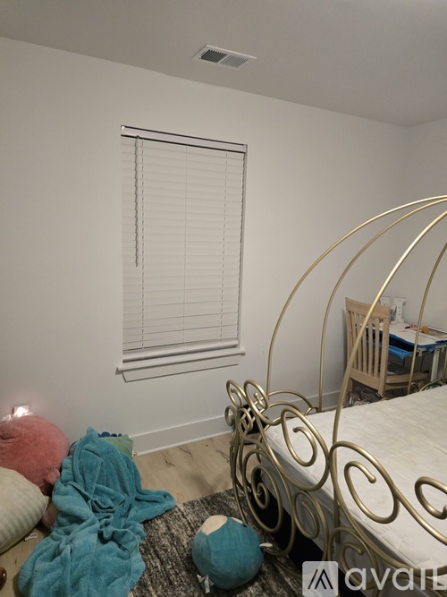 A bedroom with a bed, a chair, and a window with blinds.