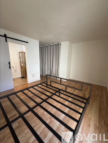 A bedroom with a wooden floor and a metal bed frame.