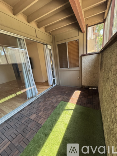 A patio area with a brick patterned floor and a green artificial grass area.