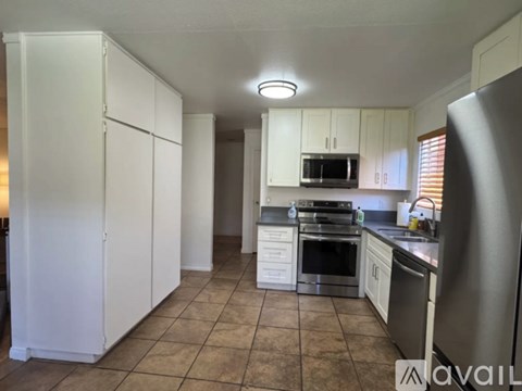 A kitchen with white cabinets and a tile floor.